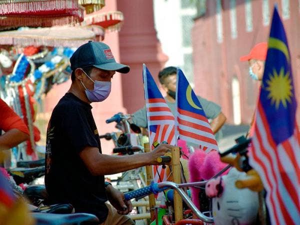 Pengayuh beca Mohd Azuan Abdul Shukor, 34, sedang menghias Jalur Gemilang di becanya sempena sambutan Hari Kebangsaan ke-64 pada sesi penyerahan Jalur Gemilang kepada Pengayuh Beca di Bandar Hilir hari ini.