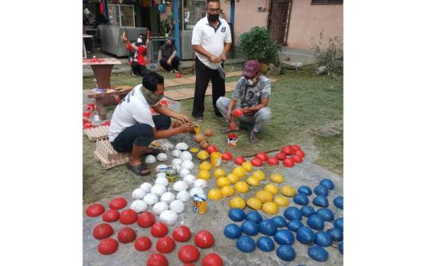 Penghuni pangsapuri mewarnakan tempurung kelapa yang digunakan sebagai sebahagian hiasan di blok kediaman mereka.