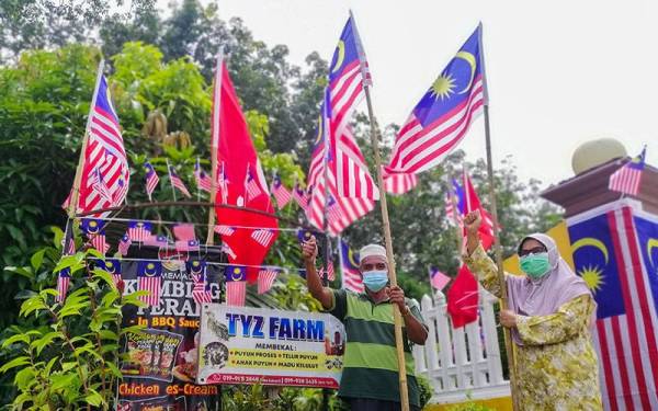 Sepasang suami isteri, Zahari Abdullah, 69, dan Tuan Yah Tuan Ya, 62, mengambil inisiatif setiap tahun memasang dan mengibarkan Jalur Gemilang di ladang tanaman dan puyuh peliharaan di rumahnya di Kampung Kubang Bongor Melor hari ini. - Foto Bernama