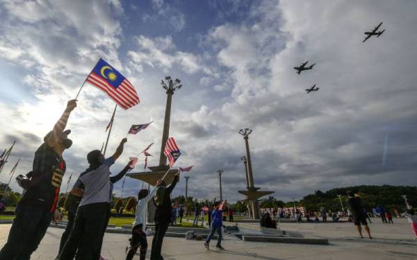 Orang ramai bersemangat mengibarkan Jalur Gemilang semasa menyaksikan persembahan udara dari Tentera Udara Diraja Malaysia (TUDM) pada Sambutan Hari Kebangsaan ke-64 di Dataran Putra pada Selasa. - Foto Bernama