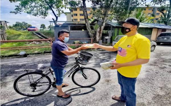 Ahli jawatankuasa masjid memberi bungkusan nasi ayam percuma kepada seorang lelaki warga asing.