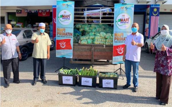 Ahmad Fadhli (dua dari kiri) menerima bantuan untuk penduduk di kawasan PKPD Kampung Repek yang disumbangkan oleh FAMA menerusi Program MAFI Prihatin, pada Selasa.