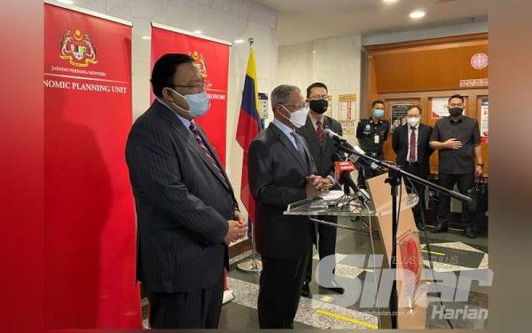 Mustapa (dua dari kiri) ketika sidang akhbar selepas mengimbas kad perakam waktu sebagai tanda memulakan tugas di Jabatan Perdana Menteri pada Rabu.