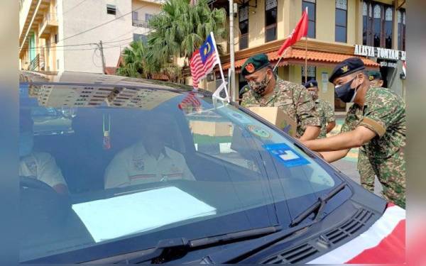 Abu Hassan (dua dari kanan) menyampaikan sumbangan kotak makanan secara pandu lalu kepada veteran ATM di bawah program Mindef Prihatin anjuran JHEV Kelantan.