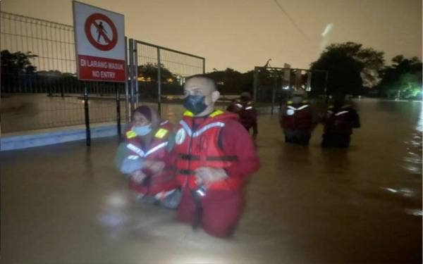 Anggota bomba membantu memindahkan pasangan warga emas yang terperangkap dalam banjir di Kampung Laut, Skudai, Johor Bahru pada Khamis.