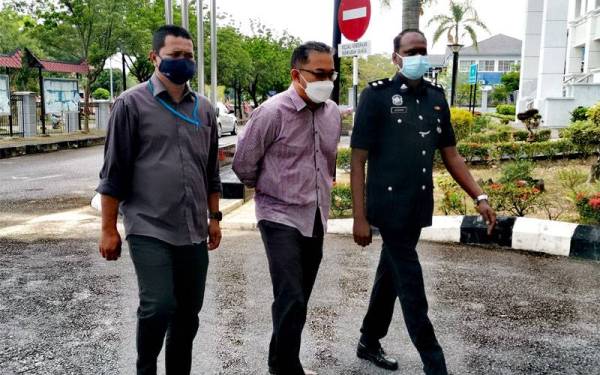 Tertuduh (tengah) diiring polis di mahkamah.