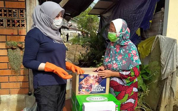Rina (kiri) menyampaikan sumbangan kepada mangsa terjejas tragedi kepala air, Noor Zalela Abd Razak di Jalan Masjid Yan pada Sabtu.