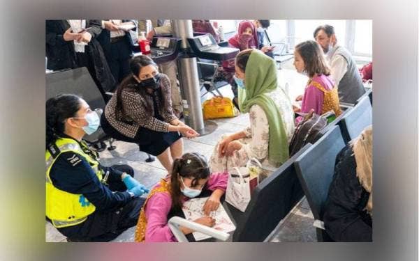 Setiausaha Dalam Negeri Britain, Priti Patel dilihat menemu bual seorang wanita pelarian Afghanistan di Lapangan Terbang Heathrow. - Foto Pool via AP