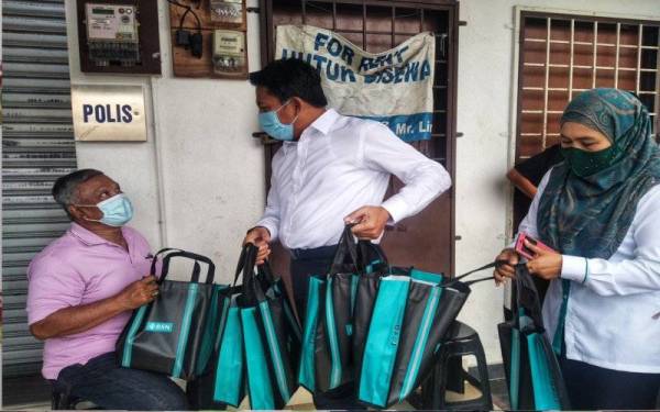 Mohd Shahar (tengah) mengagihkan cenderamata kepada orang ramai yang mengambil baucar tunai BKC di BSN Triang, Bera pada Isnin.