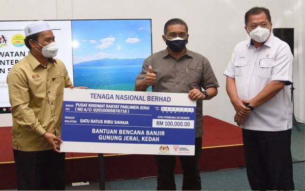 Menteri Tenaga dan Sumber Asli, Datuk Seri Takiyuddin Hassan (tengah) diiringi Presiden dan Ketua Pegawai Eksekutif TNB, Datuk Ir. Baharin Din (kanan) menyerahkan replika cek sumbangan CSR TNB bagi mangsa banjir yang bernilai RM100,000 kepada Ahli Parlimen Jerai, Sabri Azit (kiri) dalam Lawatan Kerja Menteri ke Kedah di Pusat Operasi Bencana, Titi Hayun, Yan, Kedah, 4 September 2021.