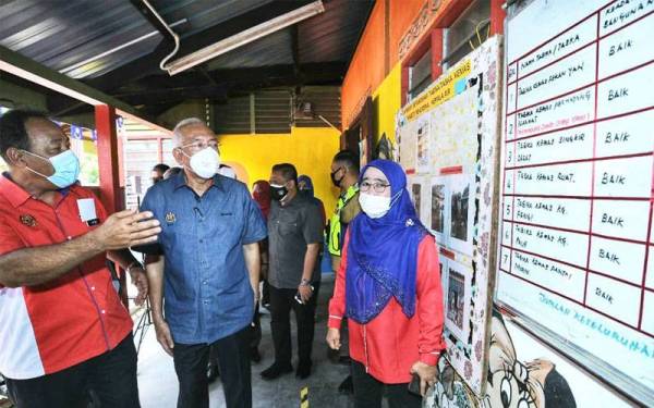 Mahdzir ( tengah) mendengar penerangan berkaitan Tabika yang terjejas akibat banjir lumpur berkenaan.