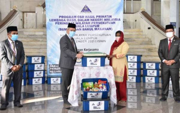 Sabin (dua dari kiri) menyampaikan bakul makanan kepada salah seorang penerima bakul makanan di Masjid Wilayah Persekutuan Kuala Lumpur pada Isnin.