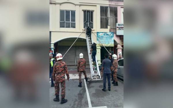 Anggota Bomba dan Penyelamat memasang tangga di tingkat satu rumah kedai berkenaan untuk membantu polis memberkas suspek.
