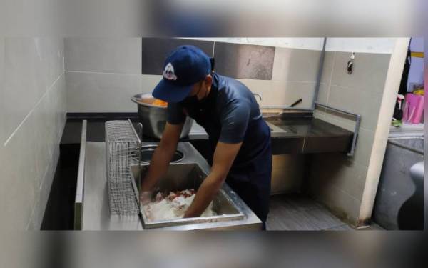 Mohd sedang memproses ayam ke dalam tepung untuk digoreng di kedainya, Matt Orie Corner, Ladang pada Selasa.