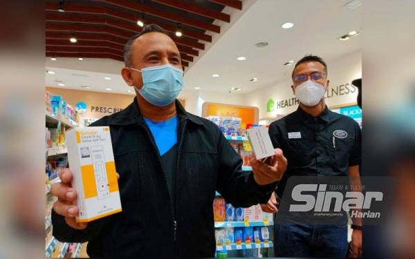 Adnan (kiri) menunjukkan kit ujian kendiri Covid-19 yang dijual disalah sebuah farmasi dengan harga yang berpatutan semasa melakukan tinjauan di KB Mall, Kota Bharu pada Selasa.