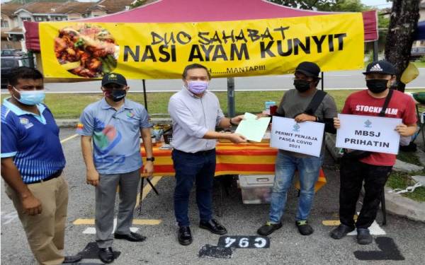 Sze Han (tiga kiri) mengadakan pertemuan dan menyerahkan lesen sementara kepada 120 peniaga di Taman Puncak Jalil, pada Selasa.