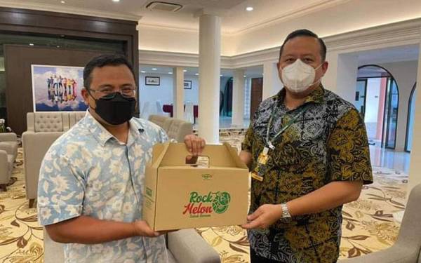 Rizam (kanan) menyerahkan buah rock melon kepada Amirudin (kiri) ketika kunjungannya, pada Selasa. - Foto ihsan Facebook Rizam Ismail.