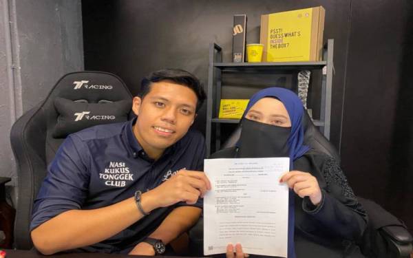 Muhammad Nur Aiman (kanan) dan isterinya, Siti Nabilah Mohamad Isa menunjukkan penyata writ saman difailkan terhadap bekas pemegang lesen perniagaan NKT kerana memfitnah mereka sebagai 'scammer'.