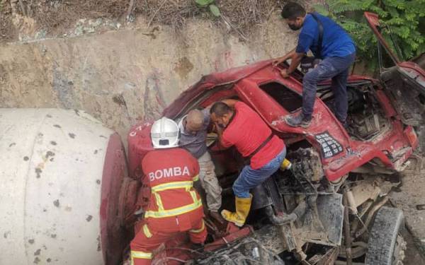 Anggota Bomba dan Penyelamat mengeluarkan pemandu lori pembancuh simen yang tersepit.