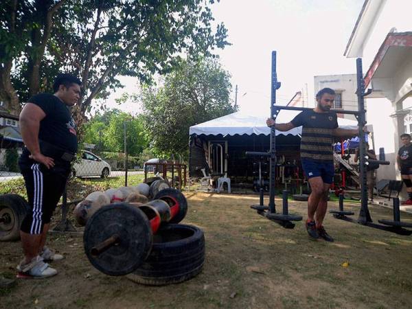 Peminat sukan bina badan Muhammad Haniff Mustafa 28 (kiri) bersama rakan melakukan aktiviti angkat berat di laman rumahnya ketika tinjauan di Puncak Alam hari ini. 