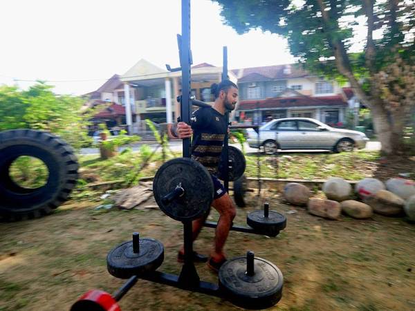 Peminat sukan bina badan Muhd Sameer Muhd Sani Sirunder, 23, melakukan aktiviti angkat berat di laman rumahnya ketika tinjauan di Puncak Alam hari ini. 