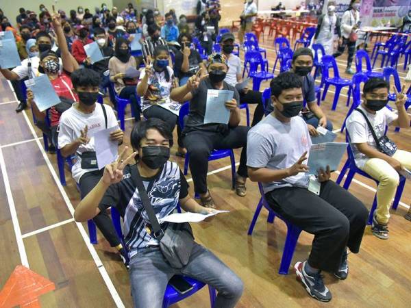 Para pelajar bersemangat dan bersedia menunggu giliran untuk menerima vaksin Covid-19 di pusat pemberian vaksin (PPV) di Dewan Kompleks Darul Kifayah MAIWP Labuan hari ini.