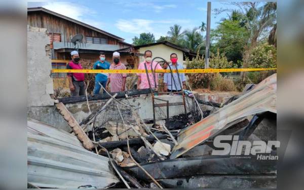 Ghazali (dua kanan) melihat rumah Sopiah yang terbakar di Felda Lubok Merbau, Kuala Nerang pada Sabtu.