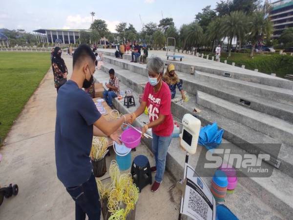 Shurina (kanan) mula menjual peralatan permainan seperti pelancar buih Setia Eco Park, Shah Alam pada Ahad setelah perniagaannya ditutup dua tahun lalu.