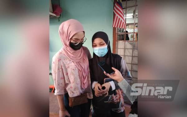 Siti Harkom (kanan) ditenangkan sepupunya ketika ditemui di Bandar Sultan Suleiman pada Ahad.