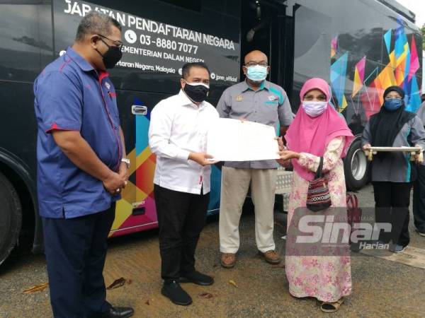 Tunku Iskandar Shah (dua dari kiri) menyerahkan sijil kelahiran baharu kepada Rahmah Yusuf, 74, pada satu majlis di Yan pada Isnin. Dokumen asal Rahmah hilang dibawa arus dalam kejadian kepala air Gunung Jerai. Turut serta ialah Saadon (kiri).