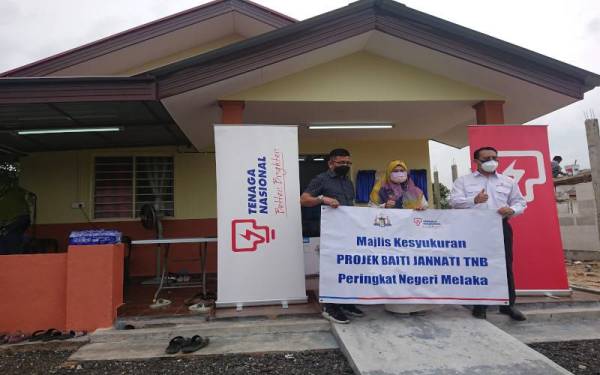 Norhizam (kiri) dan Ahmad Fadhil (kanan) ketika majlis penyampaian kunci rumah kepada Anisah (tengah) di Kampung Baroh, di Bachang pada Selasa.