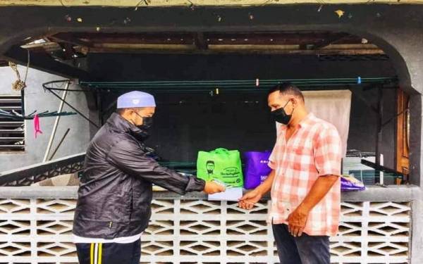 Mohd Zakhwan (kiri) menyampaikan sumbangan awal kepada Saari.