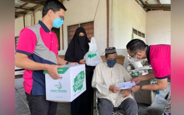 Mohamad Kairi (kanan) menyerahkan sumbangan wang tunai dan barangan keperluan kepada Norsakhair.