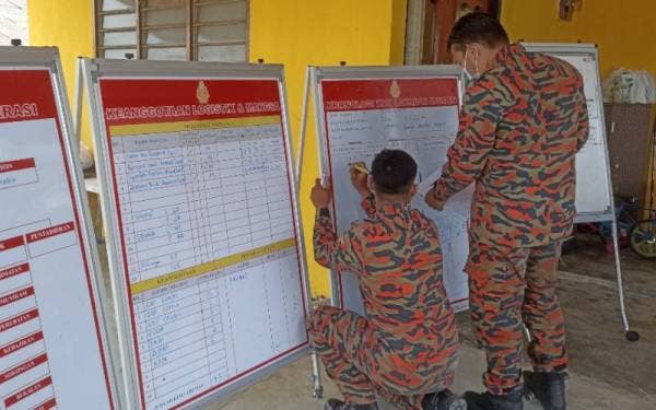 Anggota bomba sibuk mengemas kini data di bilik gerakan yang dibuka di Kampung Baru Sri Aman.