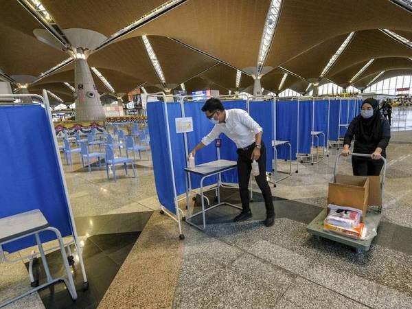 Petugas kesihatan meletakkan pembersih tangan di tempat ujian saringan kendiri di Lapangan Terbang Antarabangsa Kuala Lumpur (KLIA) hari ini.