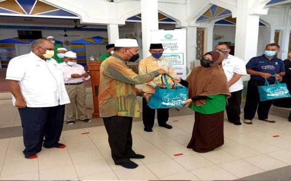 Idris menyampaikan kotak makanan kepada seorang peneirma pada program Penyerahan Foodbank YaPEIM dan Kotak Makanan YADIM di Masjid Al-Wahhab Permatang Duyong, di sini, pada Khamis.