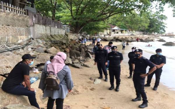 Mohd Shuhaily (tengah) sedang bertanya sesuatu kepada pengunjung di salah sebuah pantai di Tanjung Bungah.