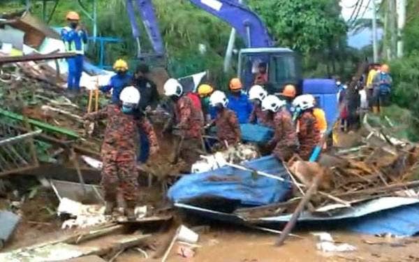 Anggota bomba membantu mengangkat mayat yang ditemui di bawah runtuhan sebuah rumah yang terlibat dalam kejadian tanah runtuh di Sungai Palas, di sini pada Khamis.- Foto JBPM Pahang