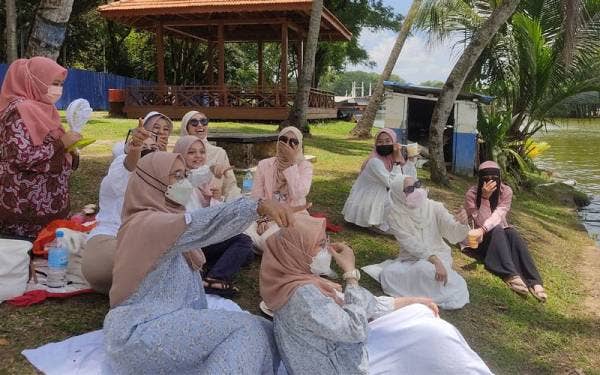 Nuralia (dua dari kanan, belakang) berkelah bersama rakan-rakannya di Taman Tasik Shah Alam pada Khamis.