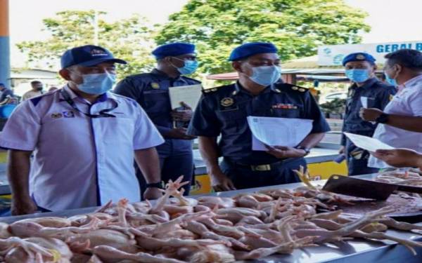 Adnan (kiri) turut serta membuat pemantauan harga ayam di sebuah lokasi di sini.