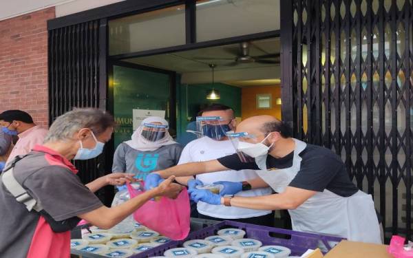 Mukhriz (kanan) memberikan pek makanan kepada golongan gelandangan di Pusat Pembelajaran Komuniti Chow Kit dan sekitar Kampong Bharu, Kuala Lumpur pada Jumaat.