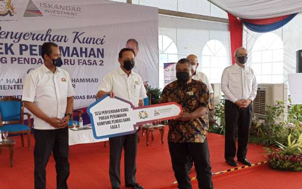 Hasni ( tiga dari kiri) menyerahkan kunci rumah kepada penduduk bagi projek penempatan semula perumahan di Kampung Pendas Baru Fasa 2 di Iskandar Puteri pada Ahad.