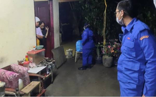 Anggota APM membantu mangsa banjir di Kampung Parit Mahang, pada Isnin.