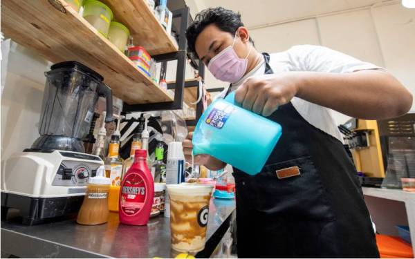 Wan Mohd Azizul Solehin menyiapkan minuman Biscoff Cheese di kafenya di Pasir Pekan di sini.- Foto Bernama 