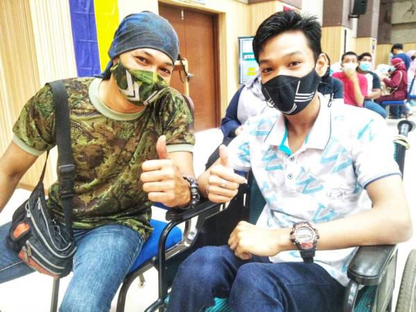 Raja Iskandar(kanan) bersama ayahnya, Raja Azman yang menemani anaknya untuk program vaksinasi di PPV Dewan Tun Razak pada Selasa.