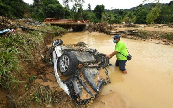 Penduduk Kampung Tampasak Sugud, Hendry Bisius, 44, memeriksa sebuah kenderaan terdampar di tepi sungai selepas dihanyutkan banjir kilat yang berlaku di Kampung Sugud petang Rabu lepas. - Foto Bernama