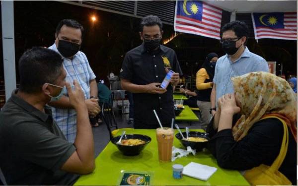 Pengarah Penguatkuasa Kementerian Perdagangan Dalam Negeri dan Hal Ehwal Pengguna (KPDNHEP) Azman Adam (tengah) memeriksa aplikasi MySejahtera pengunjung yang sudah lengkap dua dos vaksinasi ketika menyertai Operasi Samar A342 di premis makanan sekitar Ayer 8 malam ini. Foto Bernama