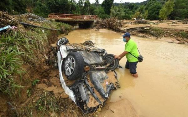 Penduduk Kampung Tampasak Sugud, Hendry Bisius, 44, memeriksa sebuah kenderaan terdampar di tepi sungai selepas dihanyutkan banjir kilat yang berlaku di Kampung Sugud petang Rabu lepas.
- Foto Bernama