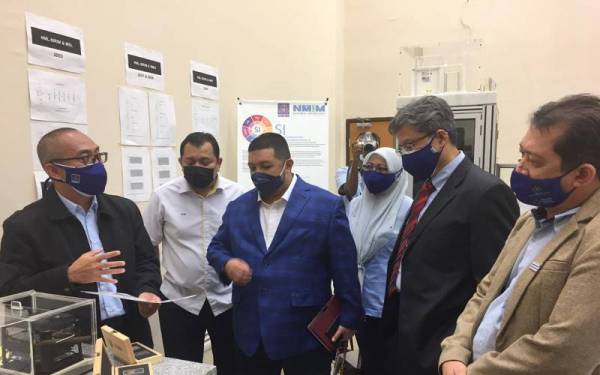 Pakar Metrologi Kanan NMIM, Dr Fazrul Mohd Nor (kiri) memberi penerangan mengenai cara mengukur ketulenan emas di Makmal NMIM, Sepang pada Rabu.