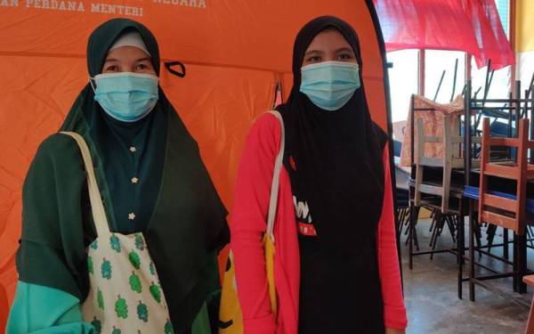 Nur Hashimah (kiri) dan anaknya Nurul Izzah terpaksa mengharungi banjir seakan pulau yang melanda rumah mereka di Kampung Buah-Buahan kampung Kuantan di sini.